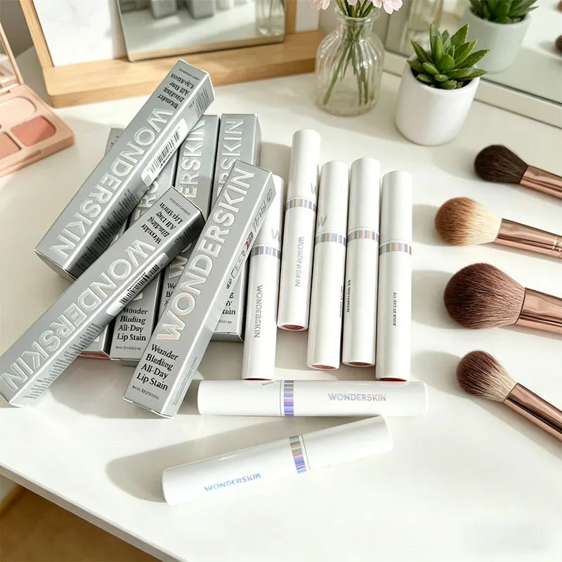 Wonderskin peel-off lip stain tubes and silver boxes on a vanity table with makeup brushes. Long-lasting lip makeup.