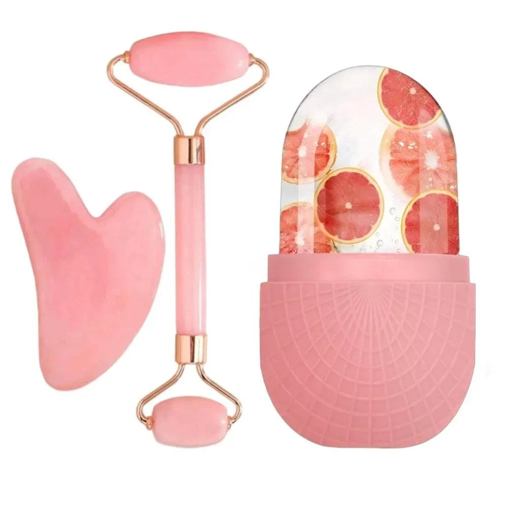 A 3-piece pink skincare set: a heart-shaped gua sha, a double-ended roller, and an ice roller with grapefruit slices.