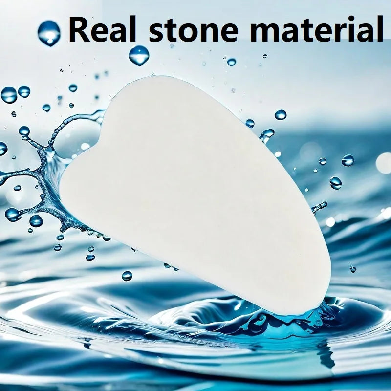 White heart-shaped gua sha tool emerging from rippling blue water with splashing droplets.