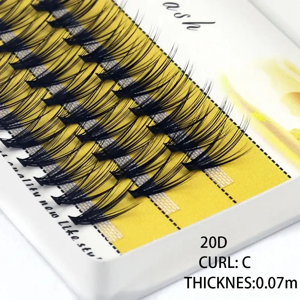 A tray of 20D black individual mink eyelash clusters with a C-curl, arranged on yellow adhesive strips.