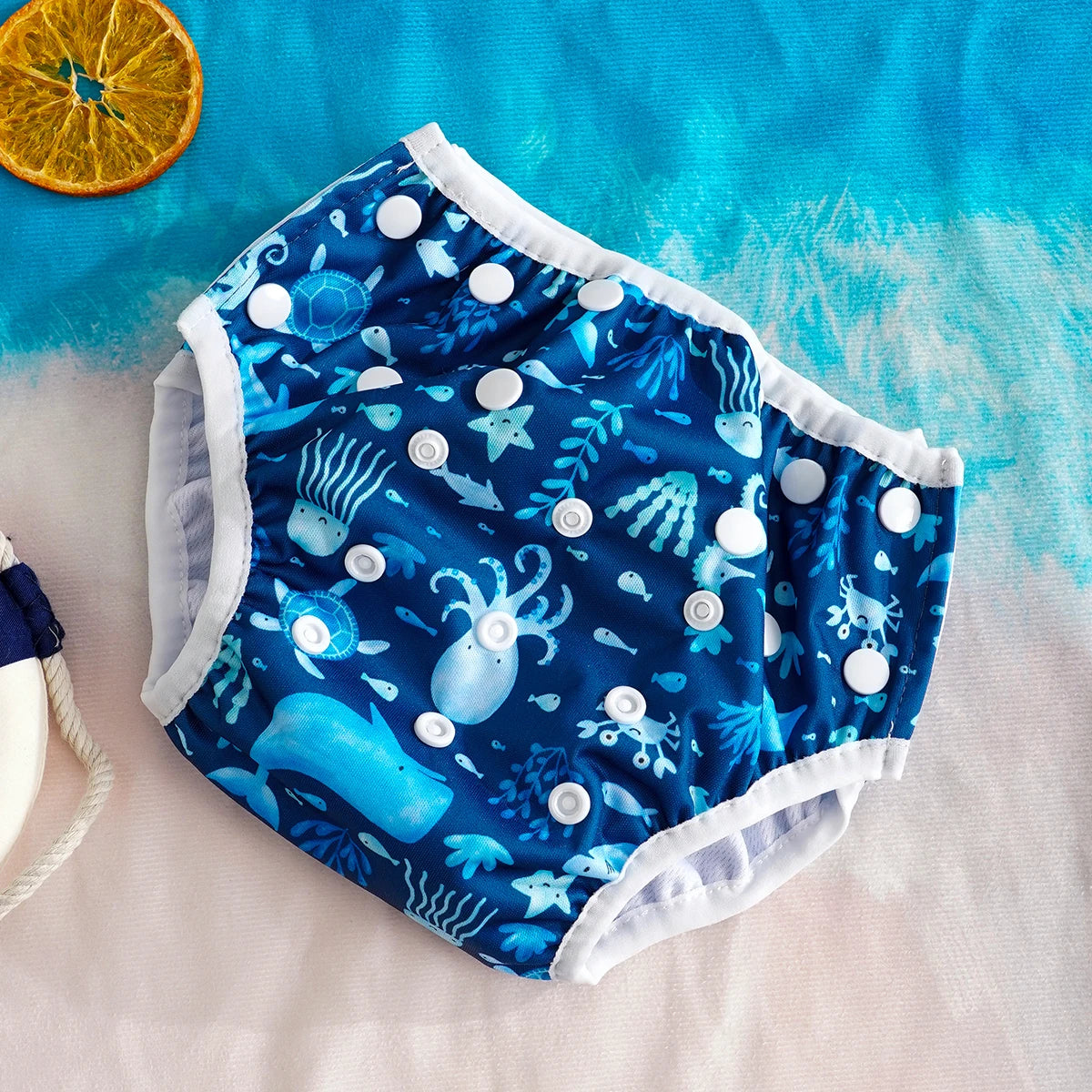 Reusable swim diaper with adjustable snaps and blue ocean sea life print. Baby care essential for pool and beach.