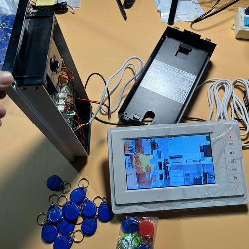 Open indoor video intercom monitor with wiring and blue RFID key fobs