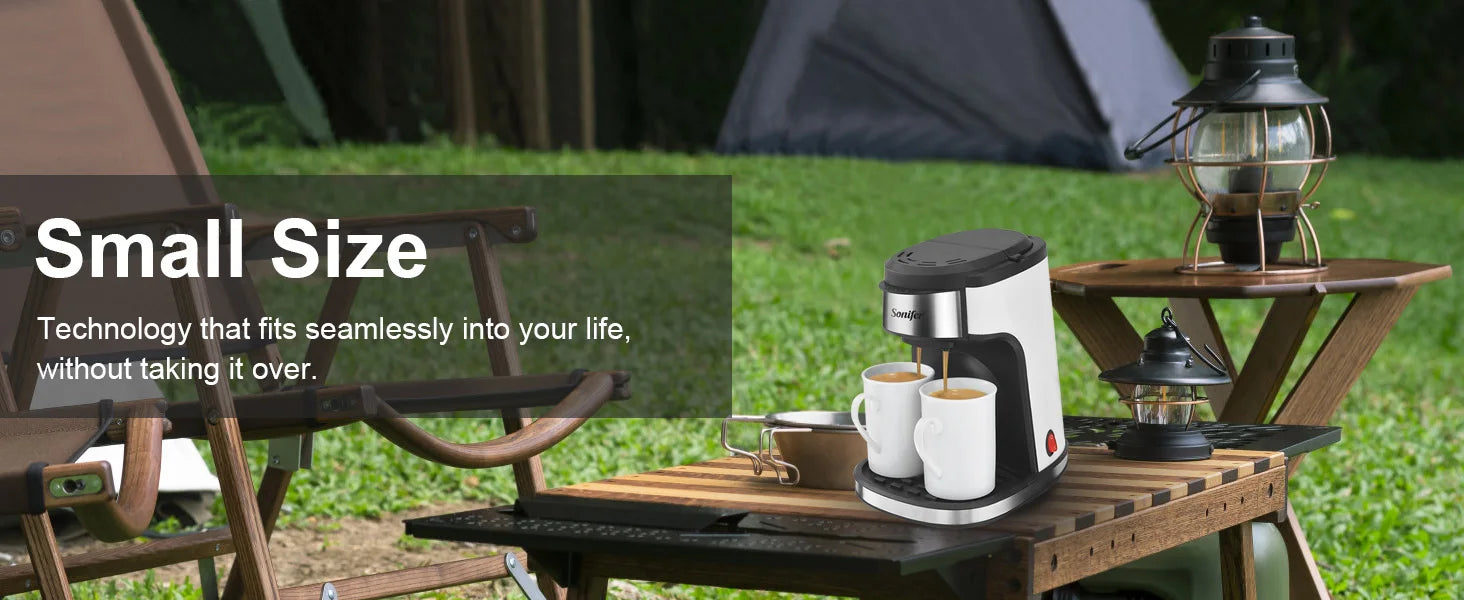 Sonifer portable white and black dual-cup coffee maker on a camping table, brewing coffee into two white mugs.