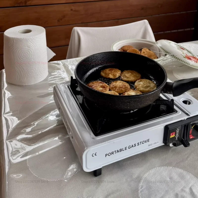 Portable gas stove cooking a batch of food in a black pan