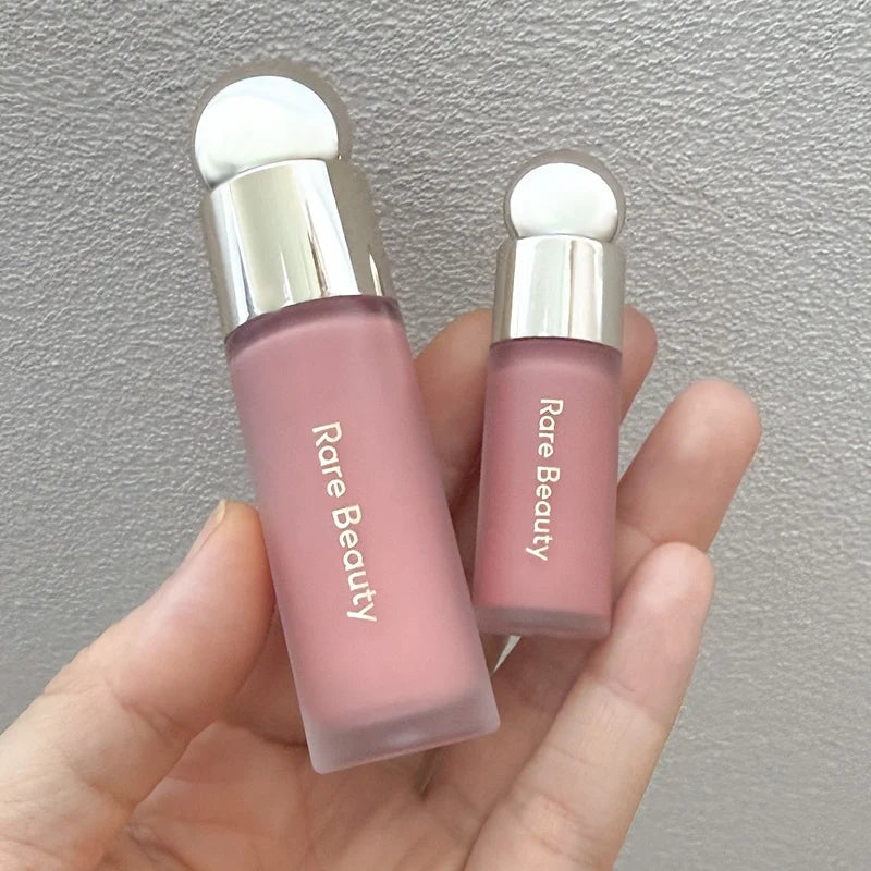 Rare Beauty Soft Pinch Liquid Blush in a dusty rose matte bottle with silver cap, held in hand.