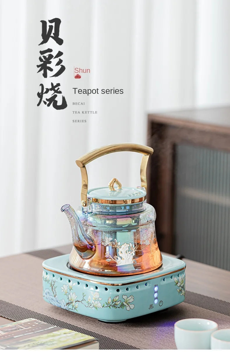 Becai Shun iridescent glass tea kettle with gold handle on a floral ceramic electric heating base.