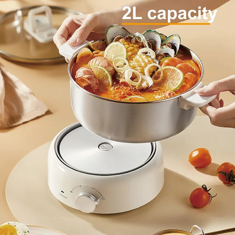 Stainless electric cooking pot with handles, filled with seafood and citrus, on white base