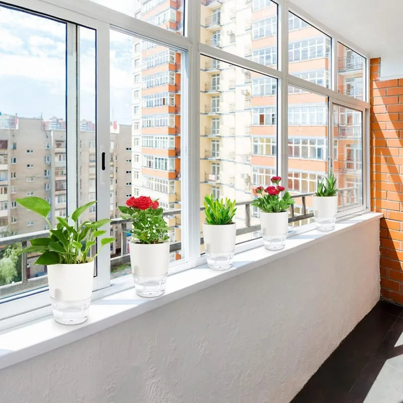Row of white self-watering planter pots on a bright windowsill