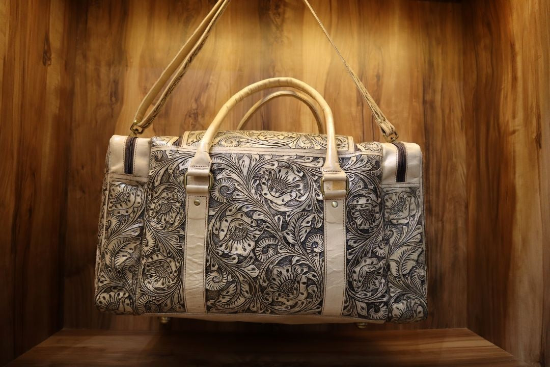 Vintage western handmade brown cowhide leather travel duffel bag with intricate floral tooling and carving detail.