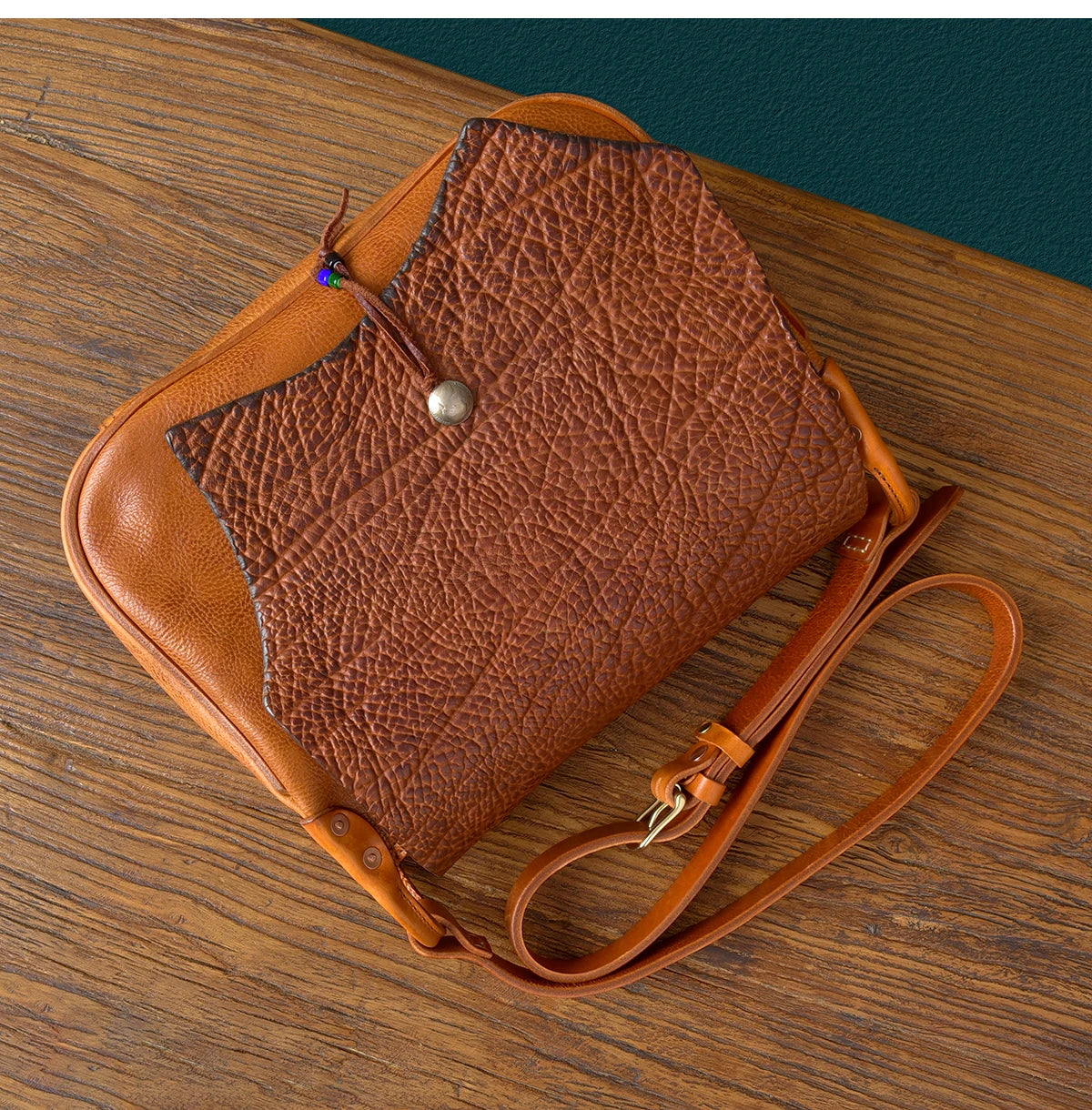 Vintage handmade messenger bag in tan cowhide leather with a textured, rugged fold-over flap and adjustable strap.