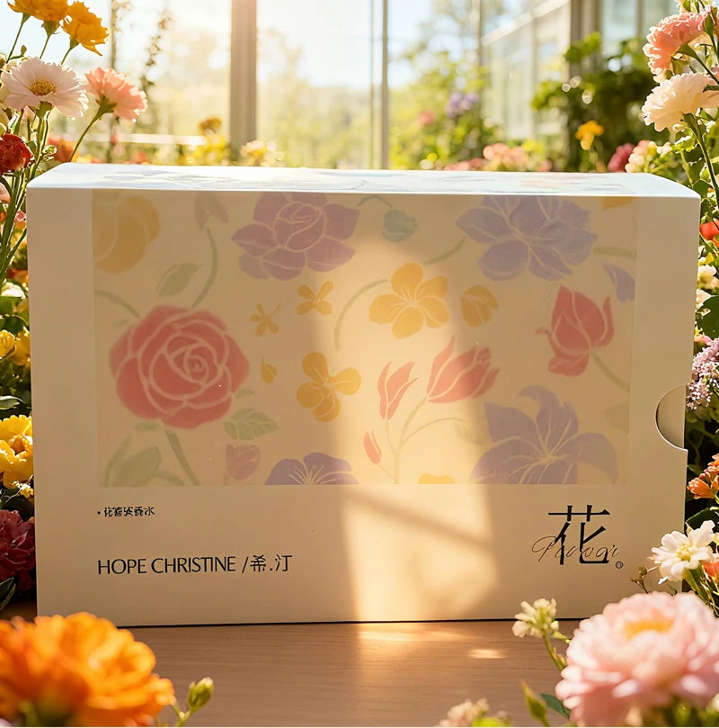 HOPE CHRISTINE perfume gift set box with soft pastel floral illustrations, surrounded by fresh garden flowers.