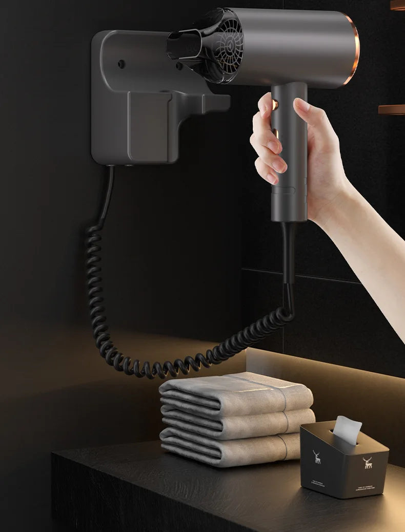 Modern grey wall-mounted hotel hair dryer with coiled cord, sleek design, and nozzle attachment for salon hair care.