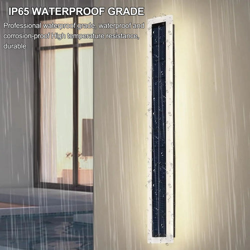 Long white vertical solar wall light mounted outdoors on a wall in the rain.