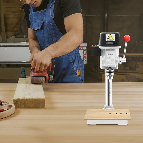 Corded mini table drill press with white base and spindle, in use on a workbench