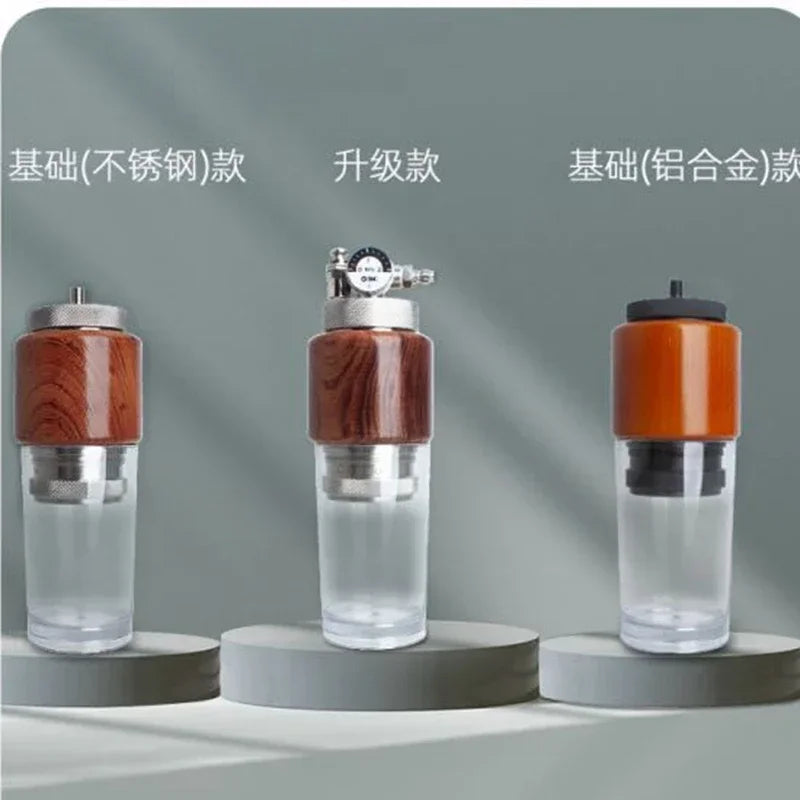 Three portable coffee makers with wood-grain accents, stainless steel or alloy, and clear glass bases on gray pedestals.