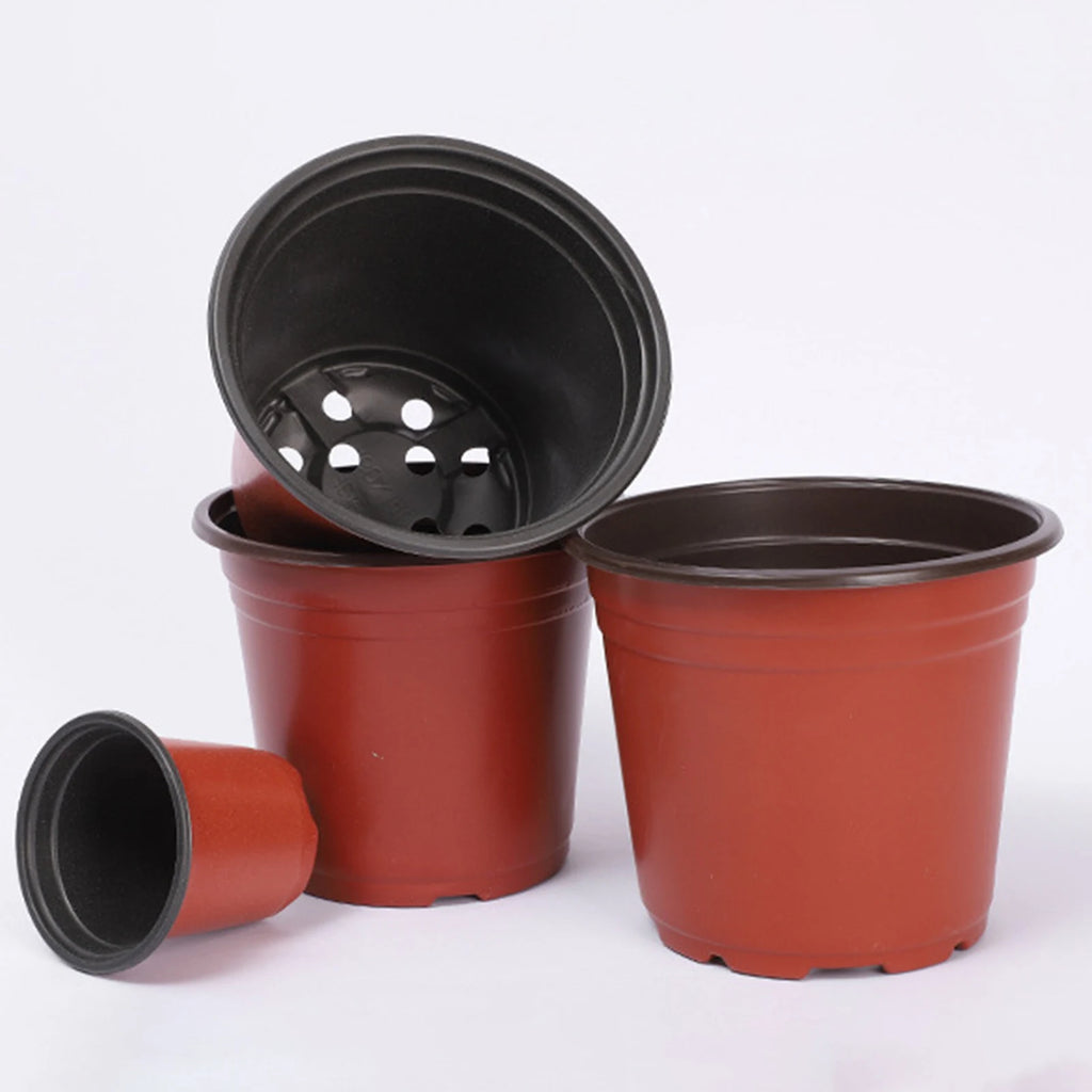 Red plastic nursery pots with black interiors, several stacked and one tilted