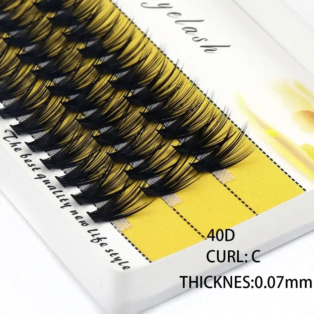 A tray of 40D black individual mink eyelash clusters with a C-curl and 0.07mm thickness on a yellow adhesive strip.