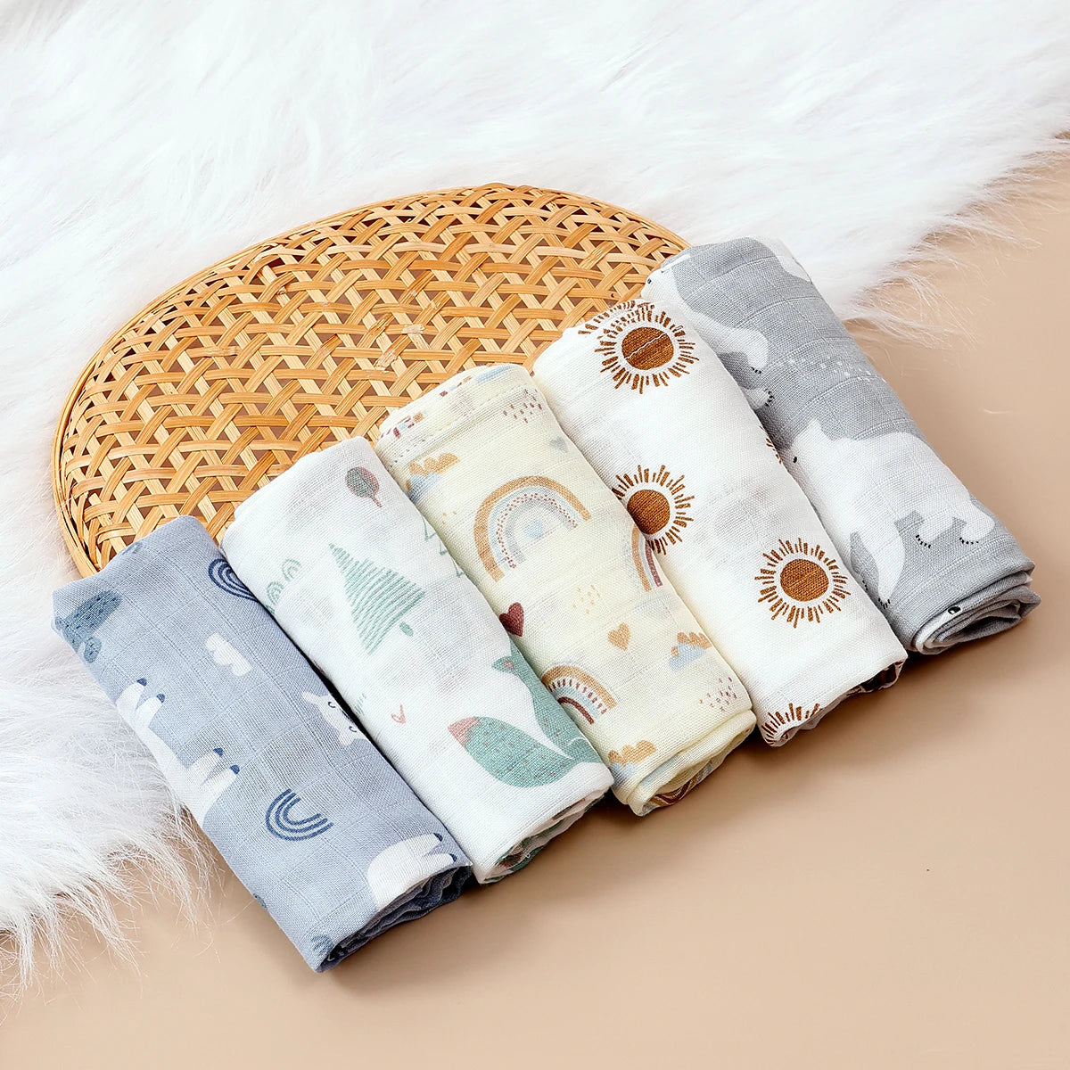 Set of 5 baby care muslin swaddle blankets with rainbow, sun, and nature prints on a woven basket.