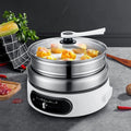 Electric hot pot multi cooker steaming eggs and vegetables under glass lid on white base