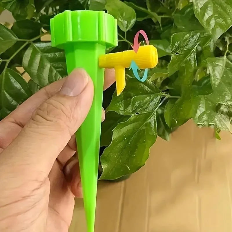 Green drip irrigation spike with adjustable flower head held in hand.