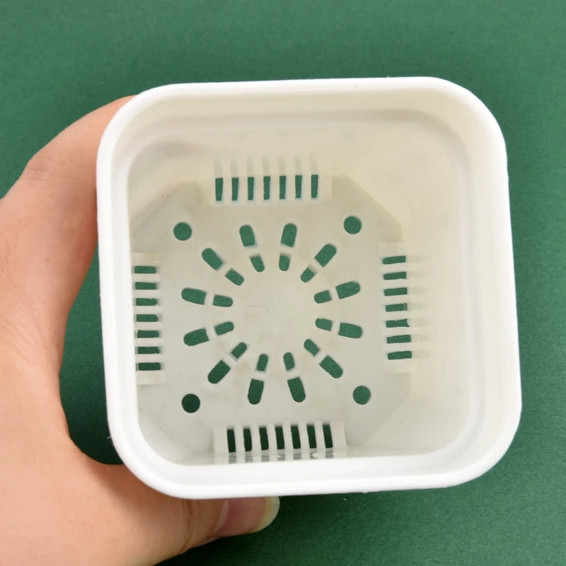 White square planter pot base with drainage holes pattern, held in hand