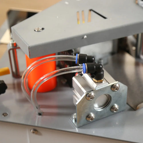 Edge banding head close-up with orange rollers, wiring, and metal guide bracket