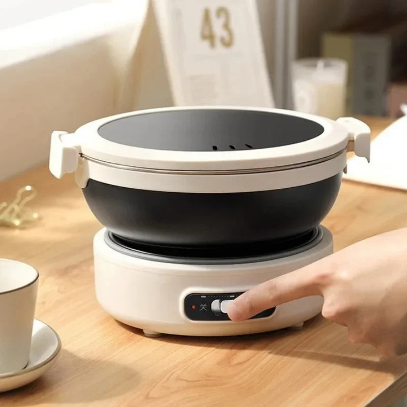 Electric cooking pot with white base and black inner bowl, round top lid visible