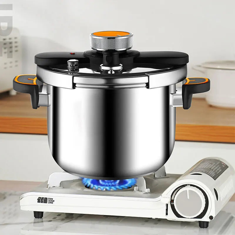 Stainless steel pressure cooker on gas stove base with black lid and pressure valve