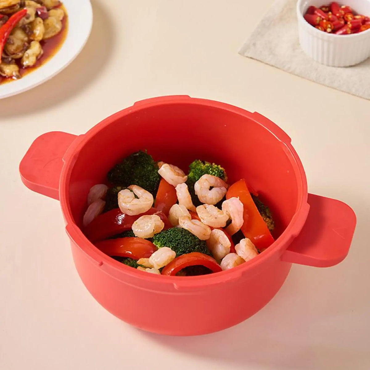 Red microwave pressure cooker pot open with shrimp and broccoli inside.
