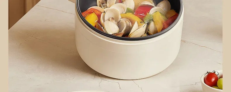 White electric cooking pot with sliced vegetables and seafood inside
