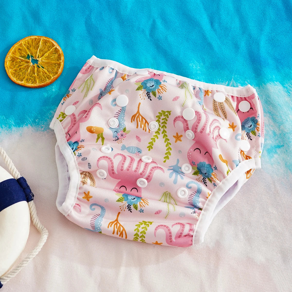 Reusable pink baby swim diaper with octopus ocean print and adjustable snap buttons.