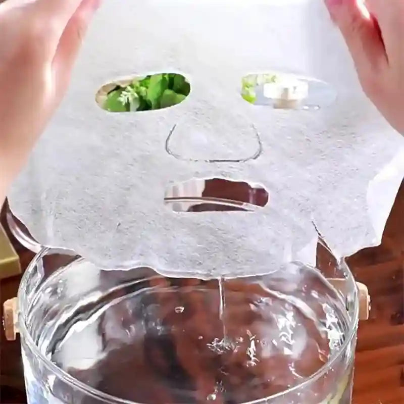 Hands holding a thin, white, disposable facial mask sheet above a bowl of water.