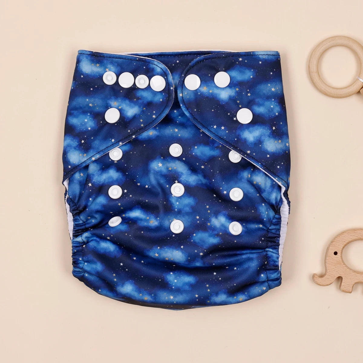 Reusable cloth baby diaper with adjustable snaps, featuring a blue star and cloud sky print.