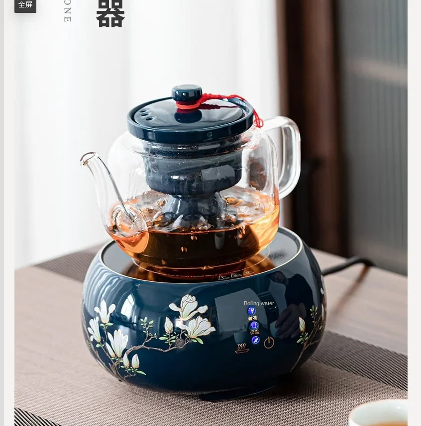 Glass teapot with dark blue ceramic infuser and floral electric base warmer for tea brewing.