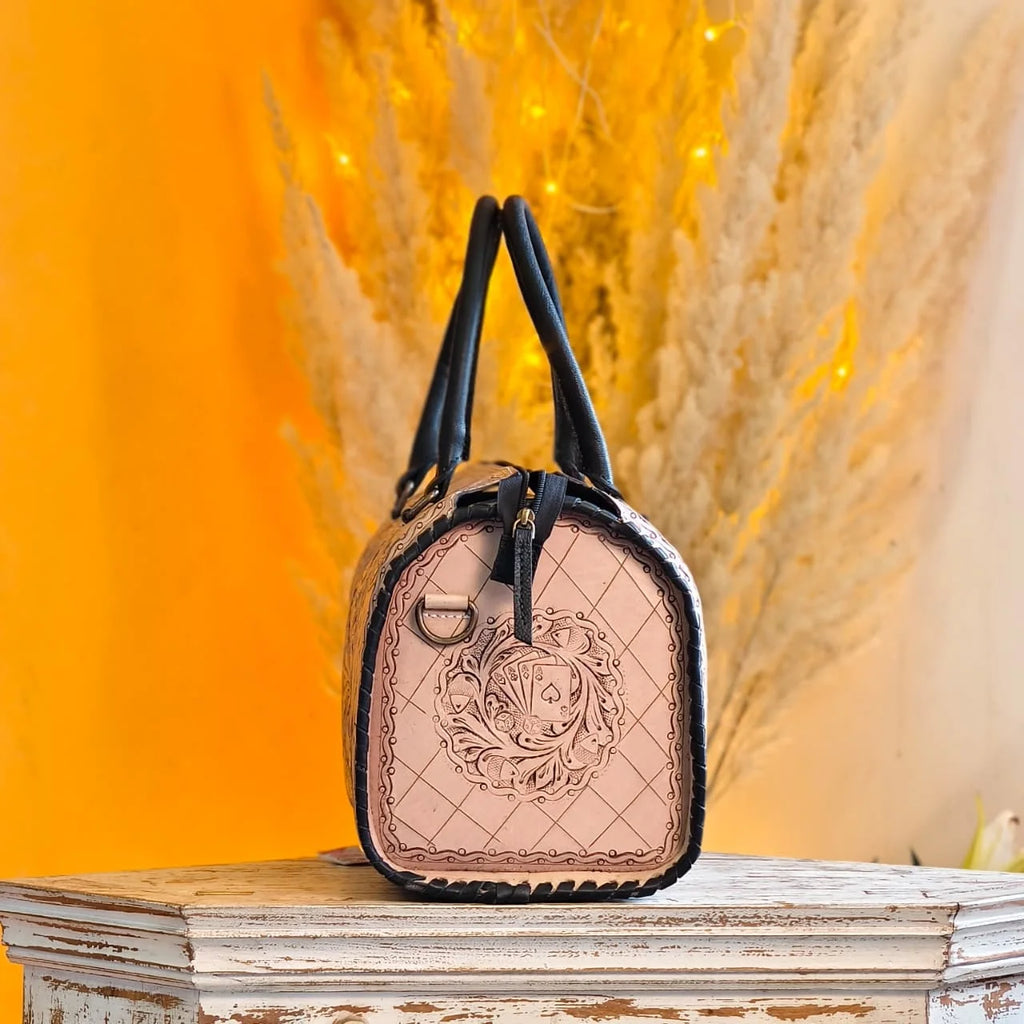 Luxury hand-tooled leather weekender duffle bag, beige with black trim, floral and playing card carved design.