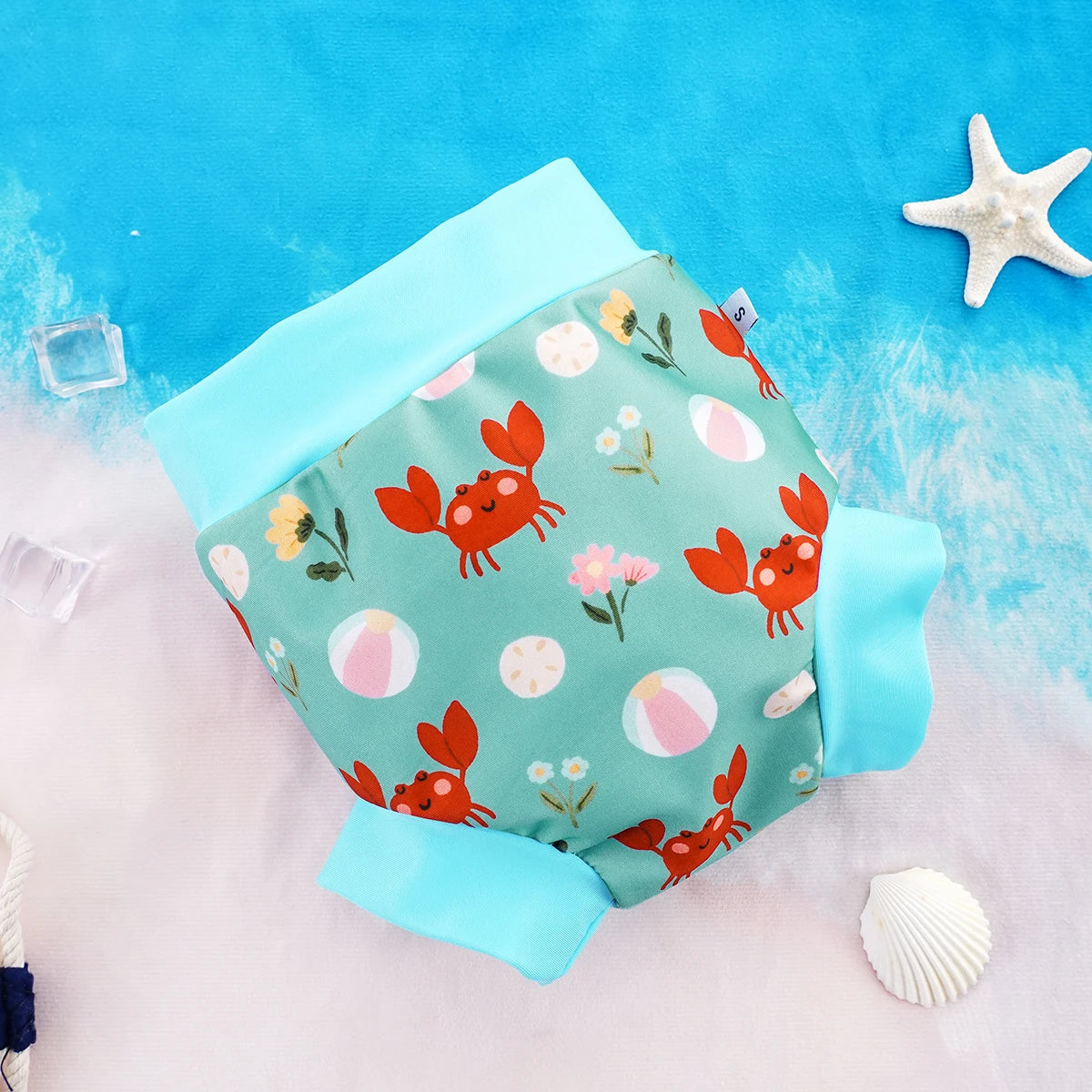 Small size baby swim diaper with cute red crab and floral print on a blue background.