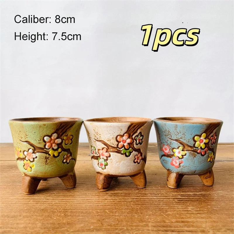 Three small ceramic flower pots with painted blossoms, speckled glaze, three legs