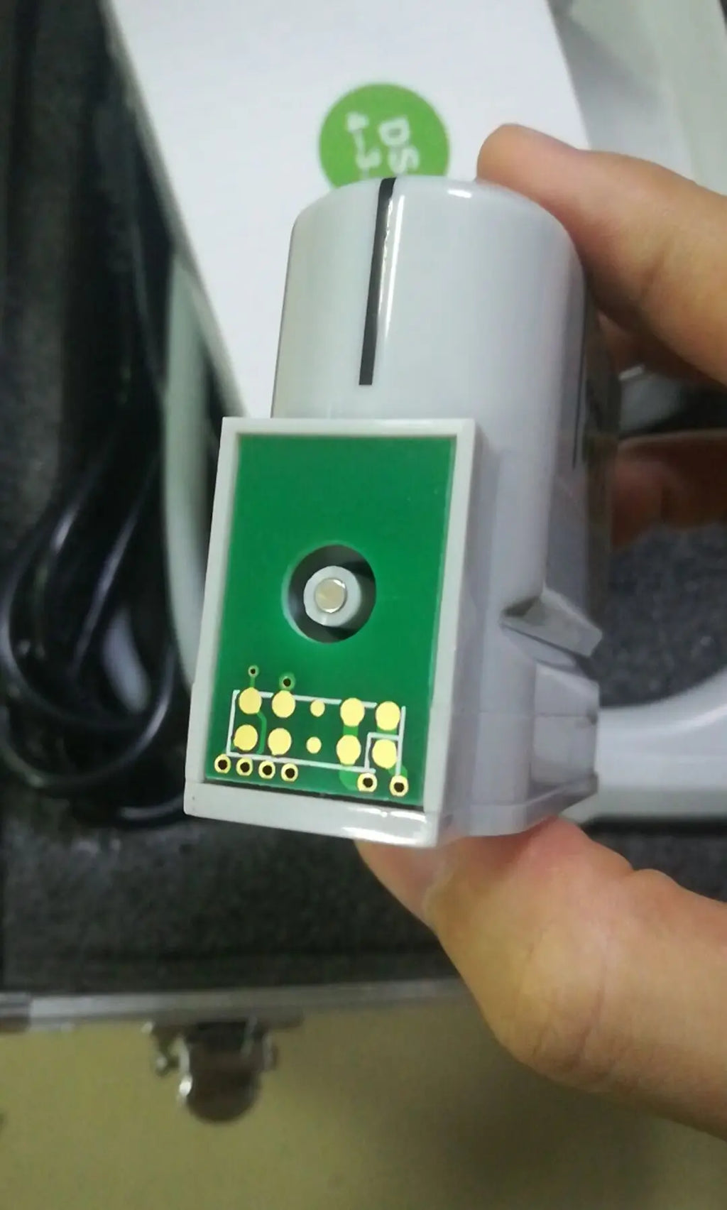 Close-up of a grey HIFU machine replacement cartridge with a green circuit board interface and gold contact pins.