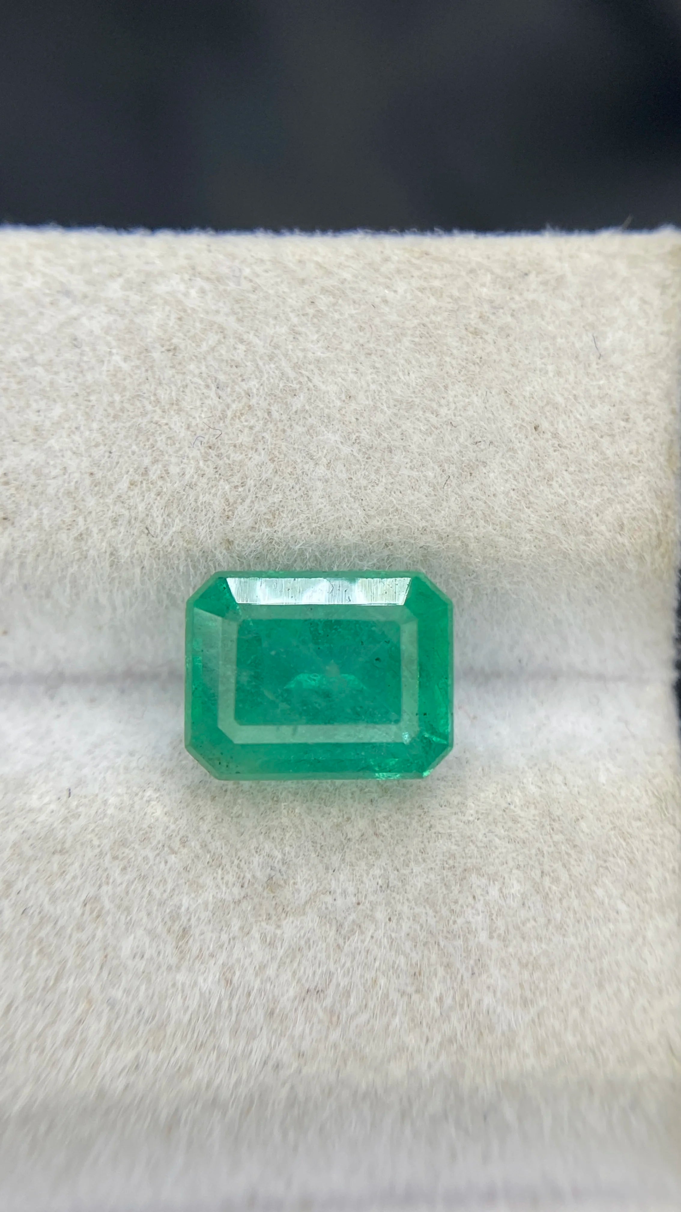 Emerald-cut green gemstone side view on white felt
