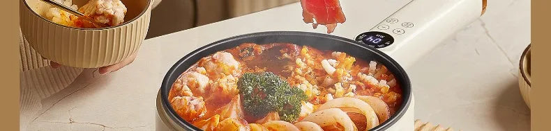 White electric cooking pot with bubbling stew, noodles, and vegetables inside