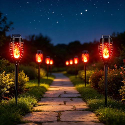 Black solar-powered stake torch lights line a stone path, glowing with a warm, flickering flame effect.