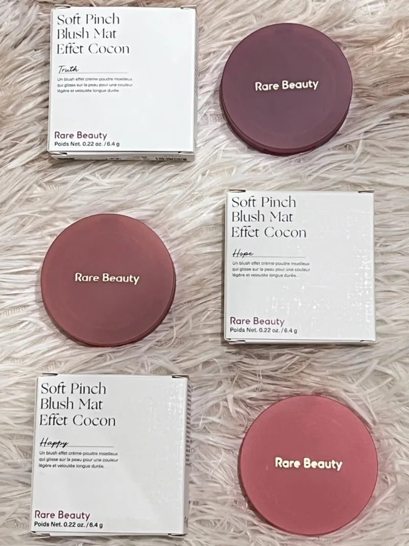 Rare Beauty Soft Pinch Luminous Powder Blush in shades Truth, Hope, and Happy. Matte compacts on fuzzy white background.