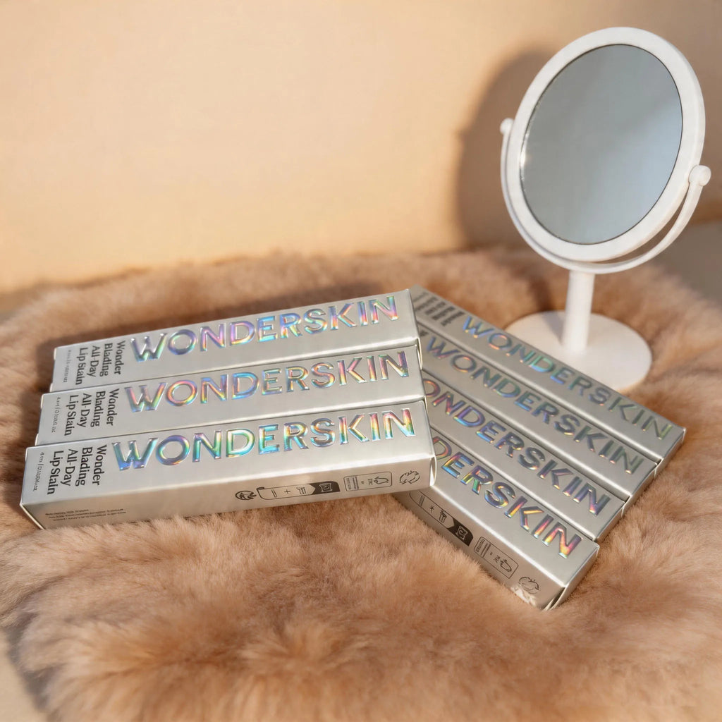 Wonderskin peel-off lip stain boxes with holographic text on a fluffy rug next to a white vanity mirror.