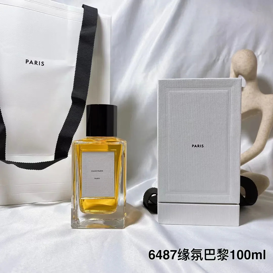Dans Paris 100ml perfume in a rectangular glass bottle with a black cap, next to its white box and paper gift bag.