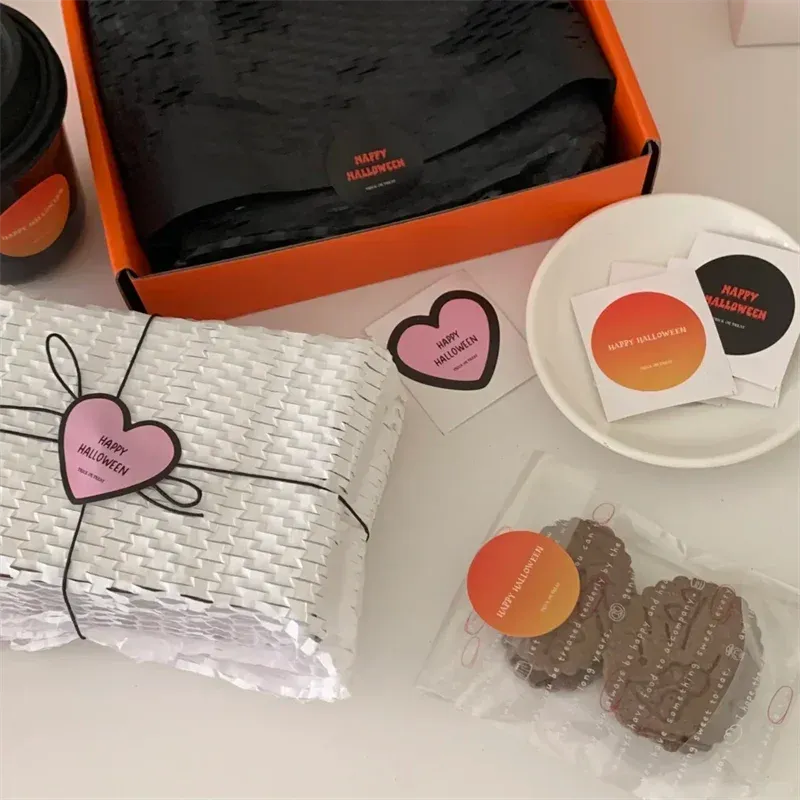 Halloween-themed custom sticker labels in black, pink, and orange on wrapped items.