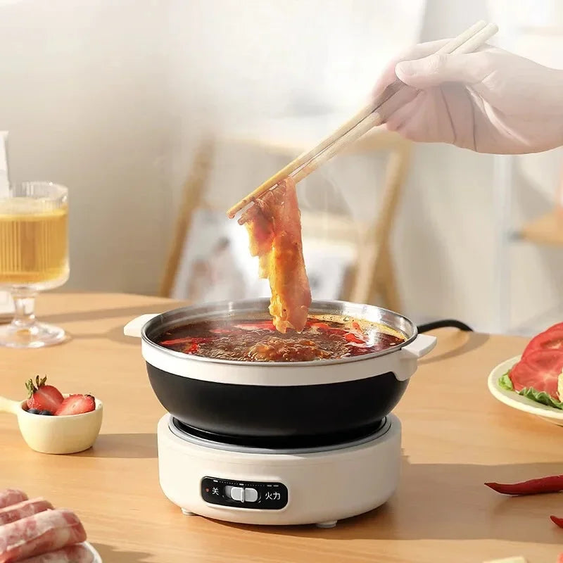 Electric hot pot on white base with black bowl, lid open as food is lifted