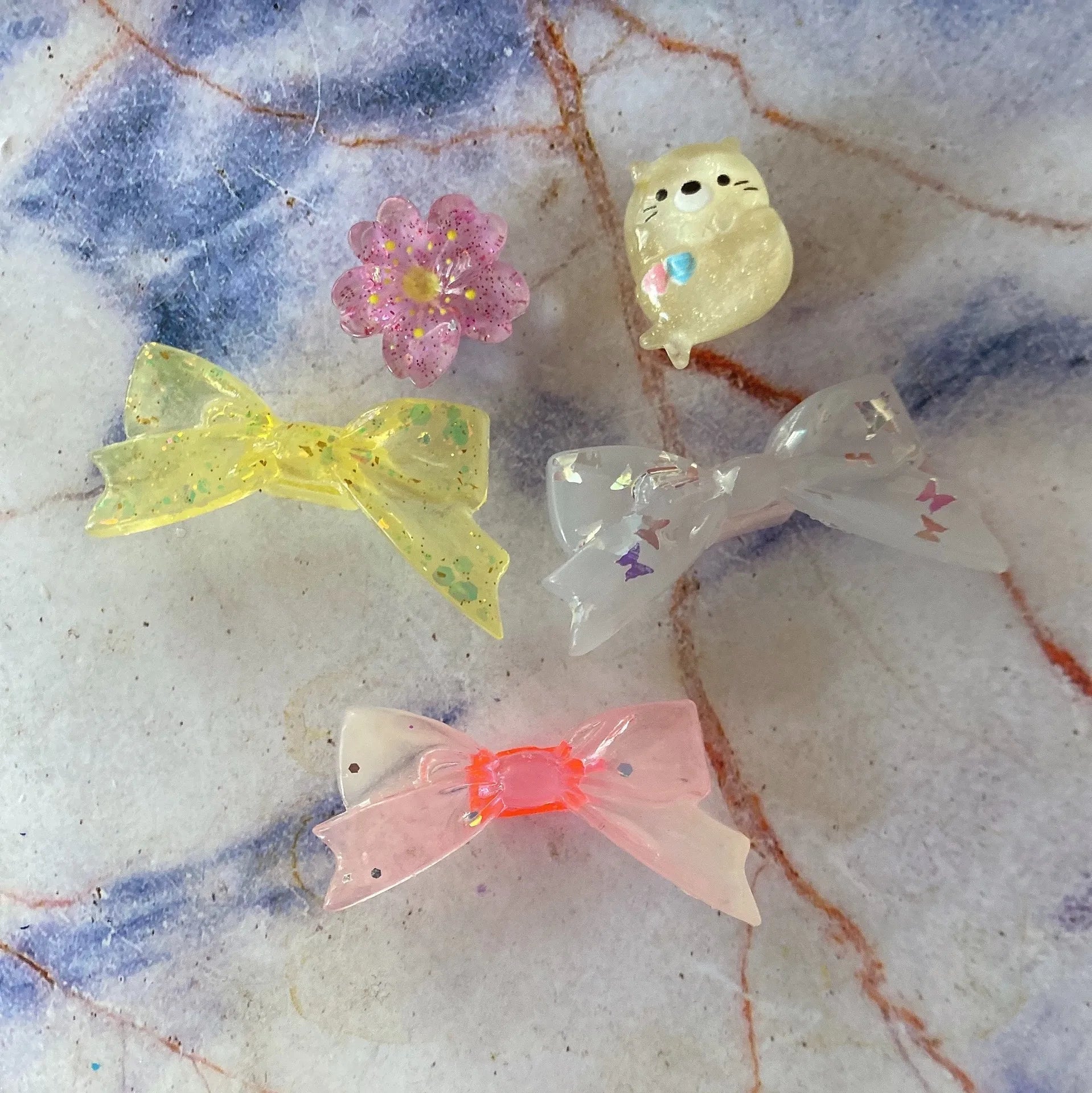 Silicone heart dust plugs for Tamagotchi Uni. Cute glitter bow and flower charms for virtual pet device protection.