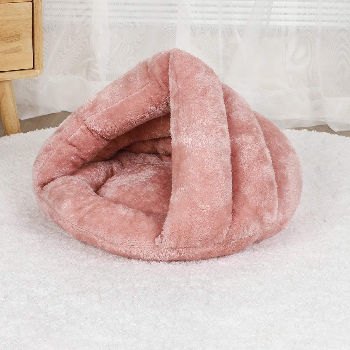 Soft pink plush dog bed with cave design for cozy, washable comfort for small dogs and cats.