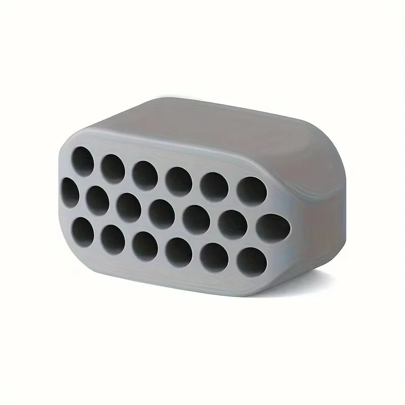 Grey silicone jawline trainer with a rectangular shape and a grid of circular holes on the front face.