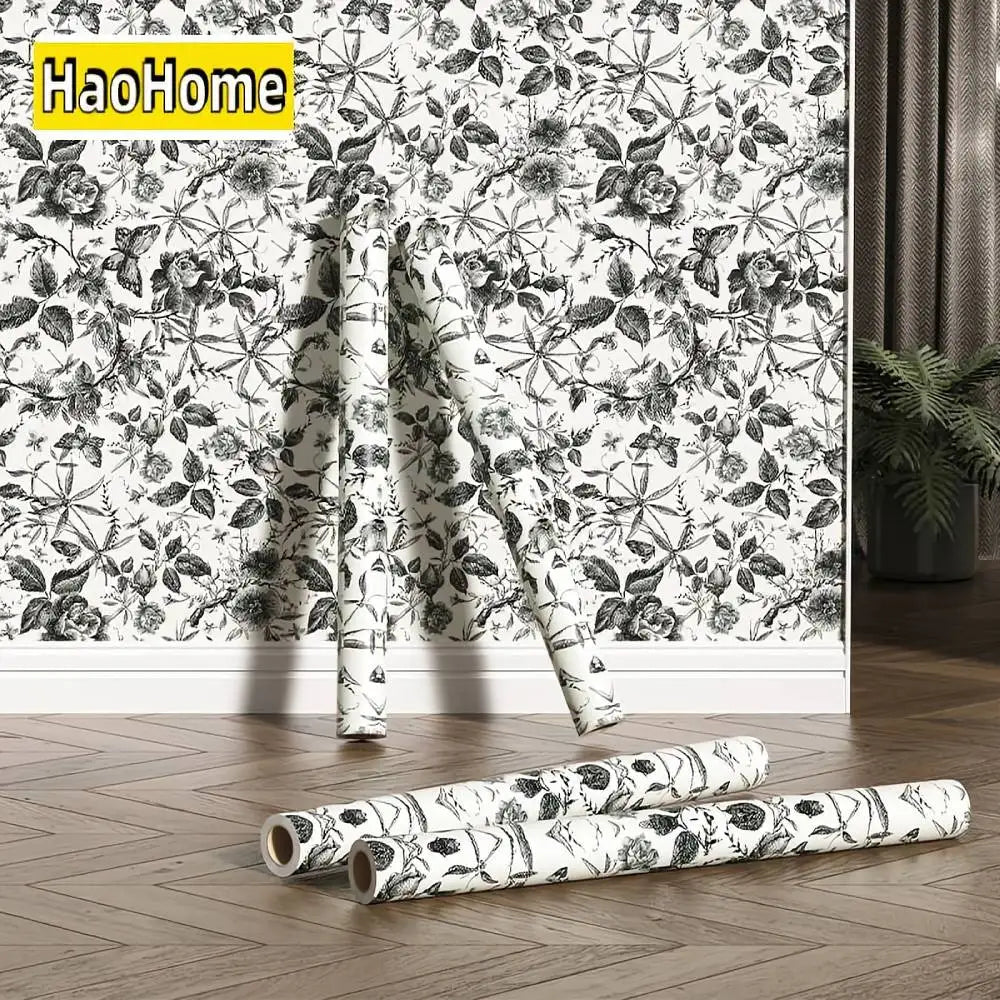 Black-and-white floral wallpaper rolls on floor, roses and leaves botanical print